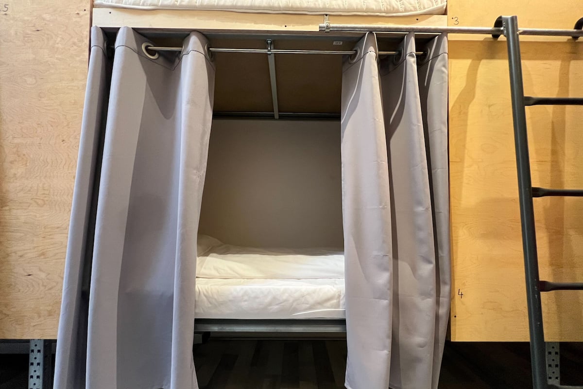 A bunk bed with a pull-up ladder, a wooden floor, and a metal frame.
