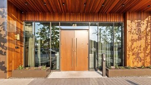 A modern building entrance with a wooden facade, glass doors, and a number "48" above the doors. - 20th FL 1BR / Heated Pool / Gym / Bar (Austin)