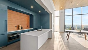 A modern kitchen with a central island, built-in oven, and a large window overlooking a cityscape. - 20th FL 1BR / Heated Pool / Gym / Bar (Austin)