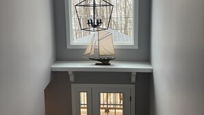 Una stanza con un'ampia finestra, un lampadario a soffitto e una porta.