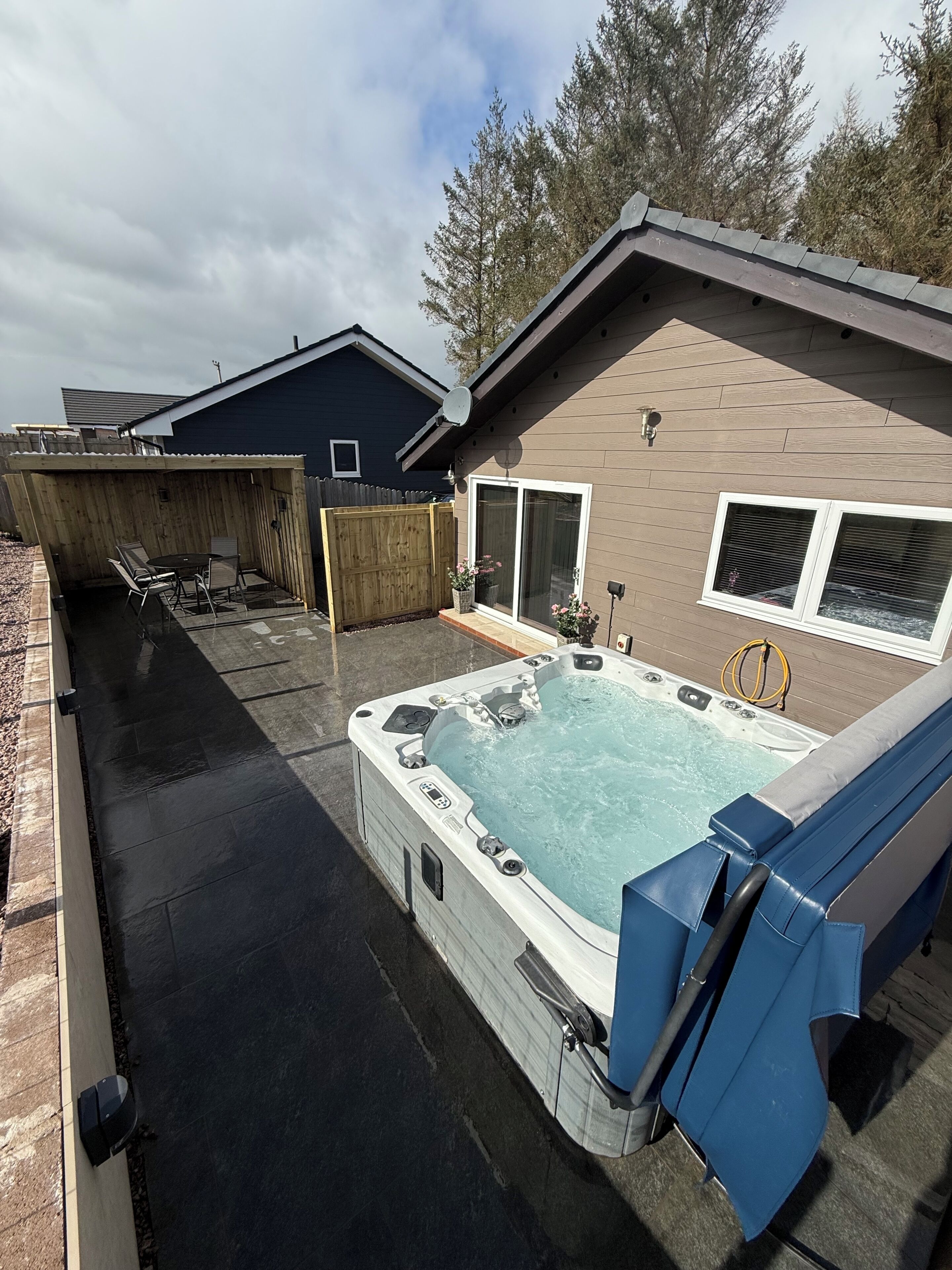 Ein Garten mit Whirlpool, Terrassenmöbeln und Holzzaun.