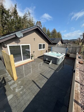 A residential backyard with a hot tub, a covered patio, and a wooden fence. - Woodend lodge with 6 seater private hottub (Beeswing)