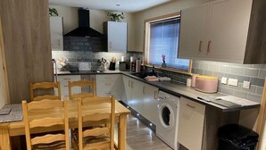 A compact kitchen with a dining area, built-in appliances, and a window with blinds.