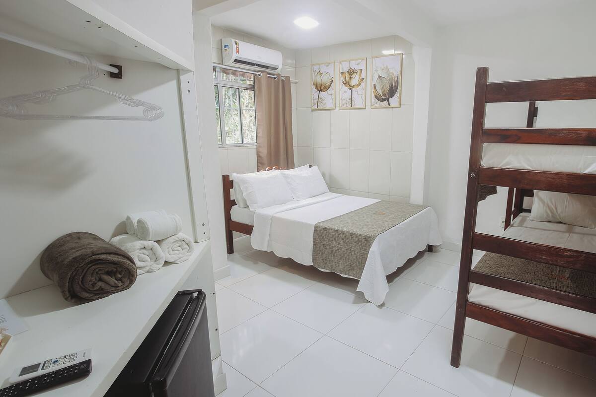 Un dormitorio con una cama, una litera de madera, un radiador y una ventana con cortinas.