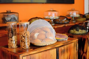 Una mesa de buffet con diferentes alimentos, incluyendo galletas y pasteles en recipientes de vidrio y cestas.
