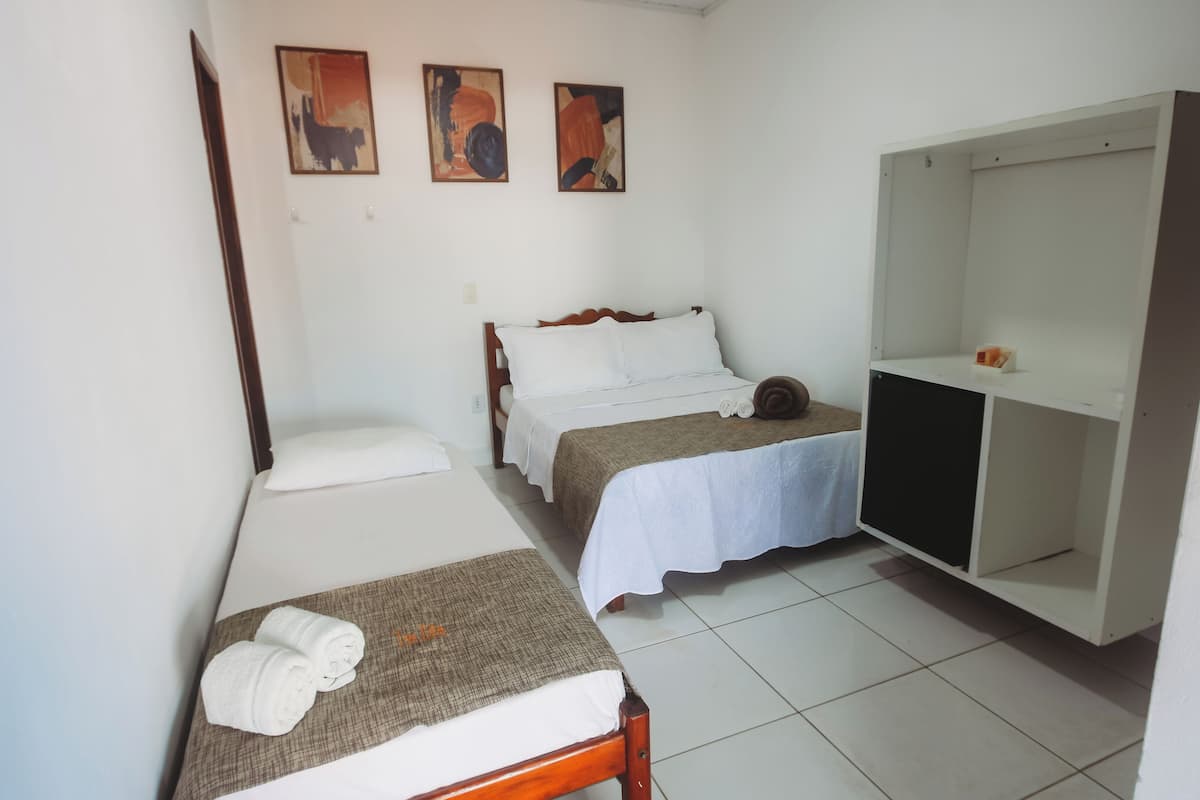 Una habitación pequeña y limpia con dos camas individuales, un armario y una pared con arte abstracto.
