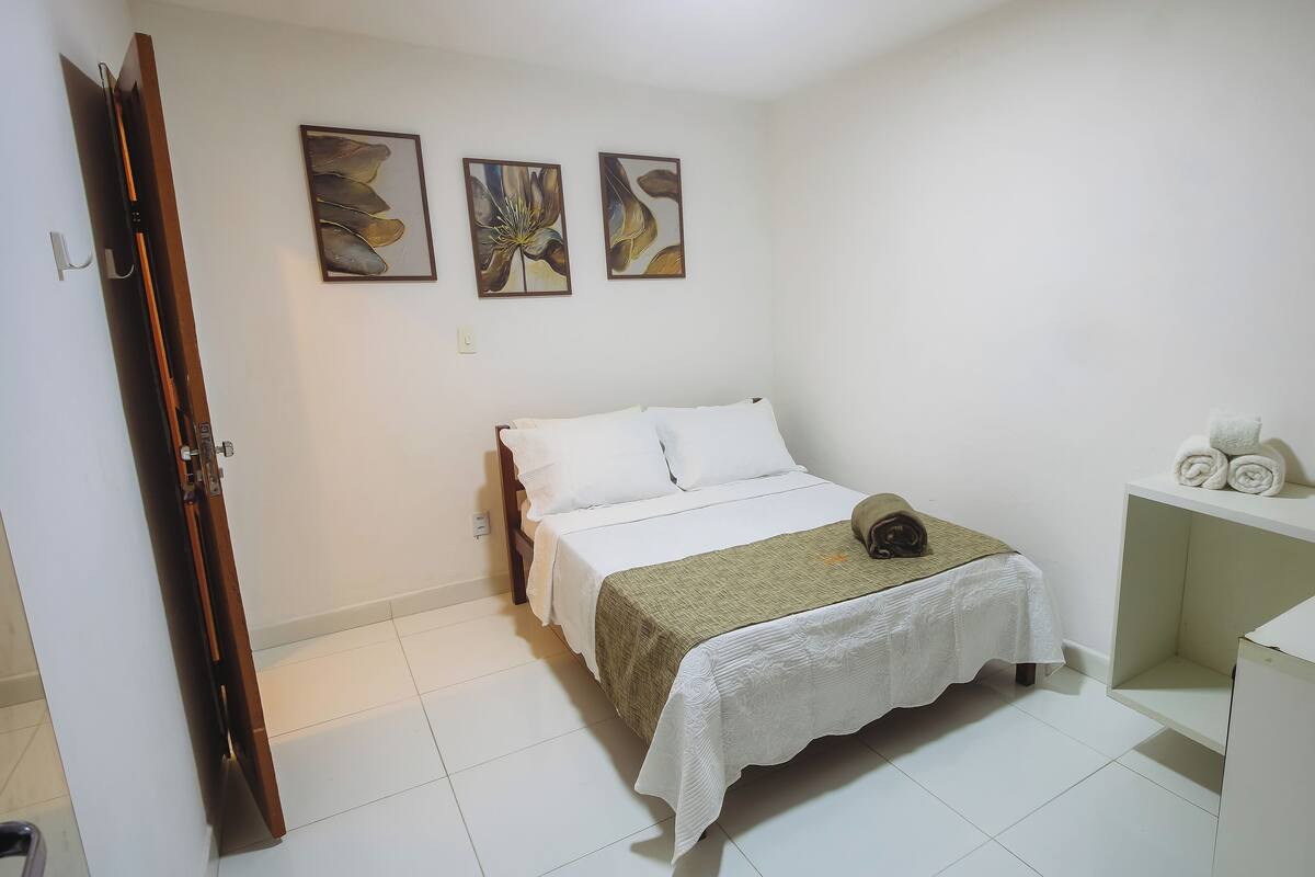 Un dormitorio con cama, escritorio y tres cuadros colgados en la pared.
