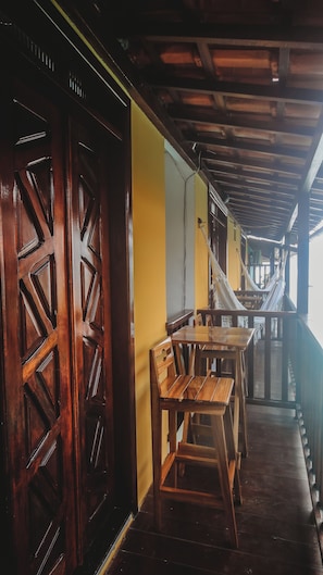 Un interior de madera con una mesa, bancos, una pared amarilla y un techo de madera.