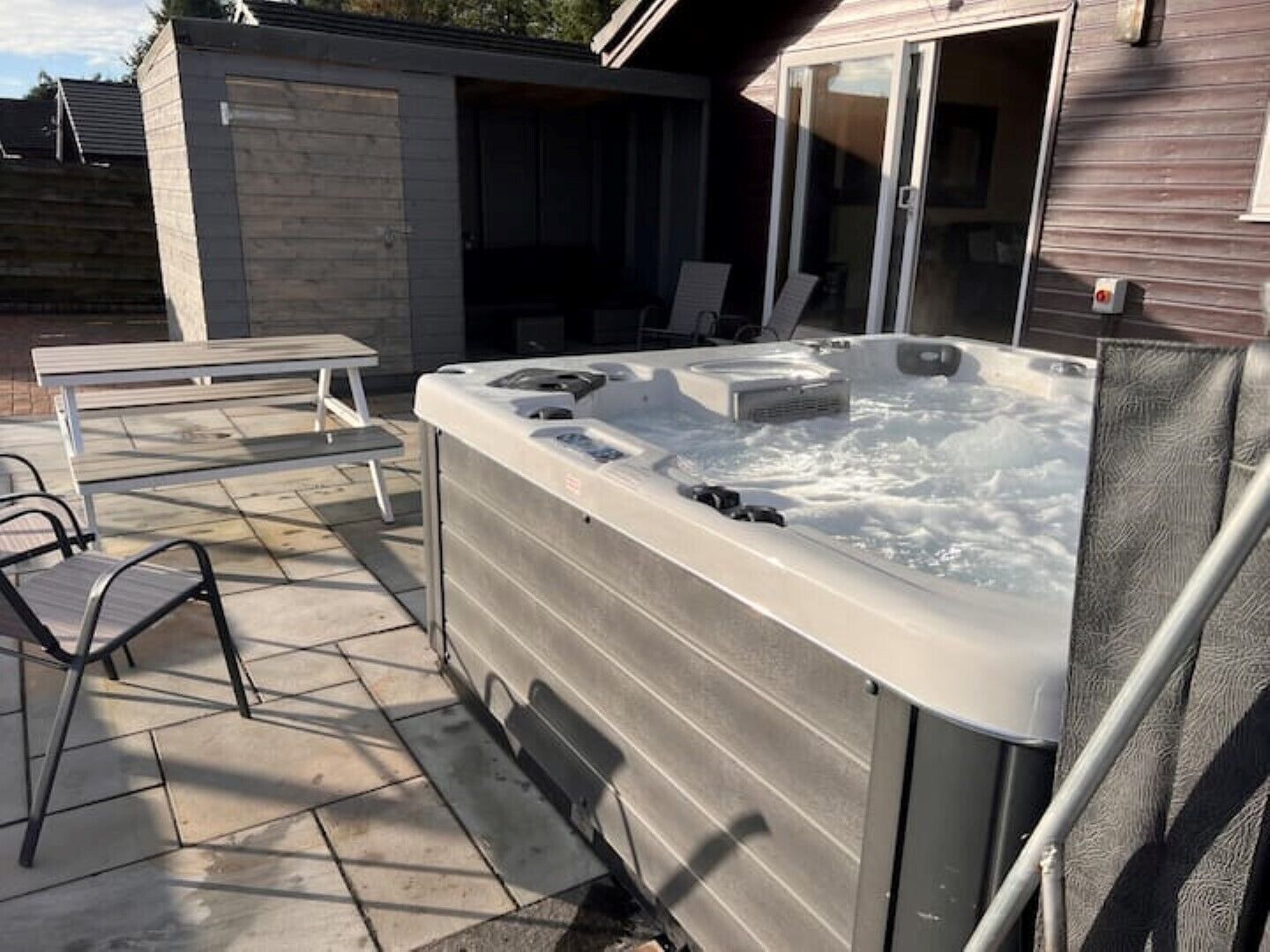 A hot tub in a backyard with a patio table and chairs.