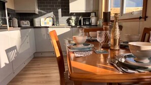 Een moderne keuken met witte kasten, een houten eettafel gedekt voor vier personen, en uitzicht op de omgeving via een raam.