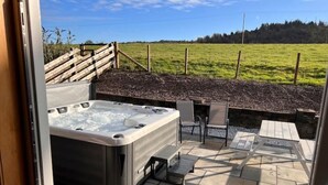 Een hottub met een terras, inclusief stoelen en een tafel.