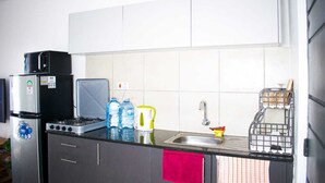 Uma cozinha compacta com fogão a gás, geladeira preta, micro-ondas e pia.