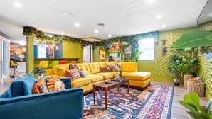 Un salón vibrante con un sofá amarillo, un sillón azul y un tapete estampado.