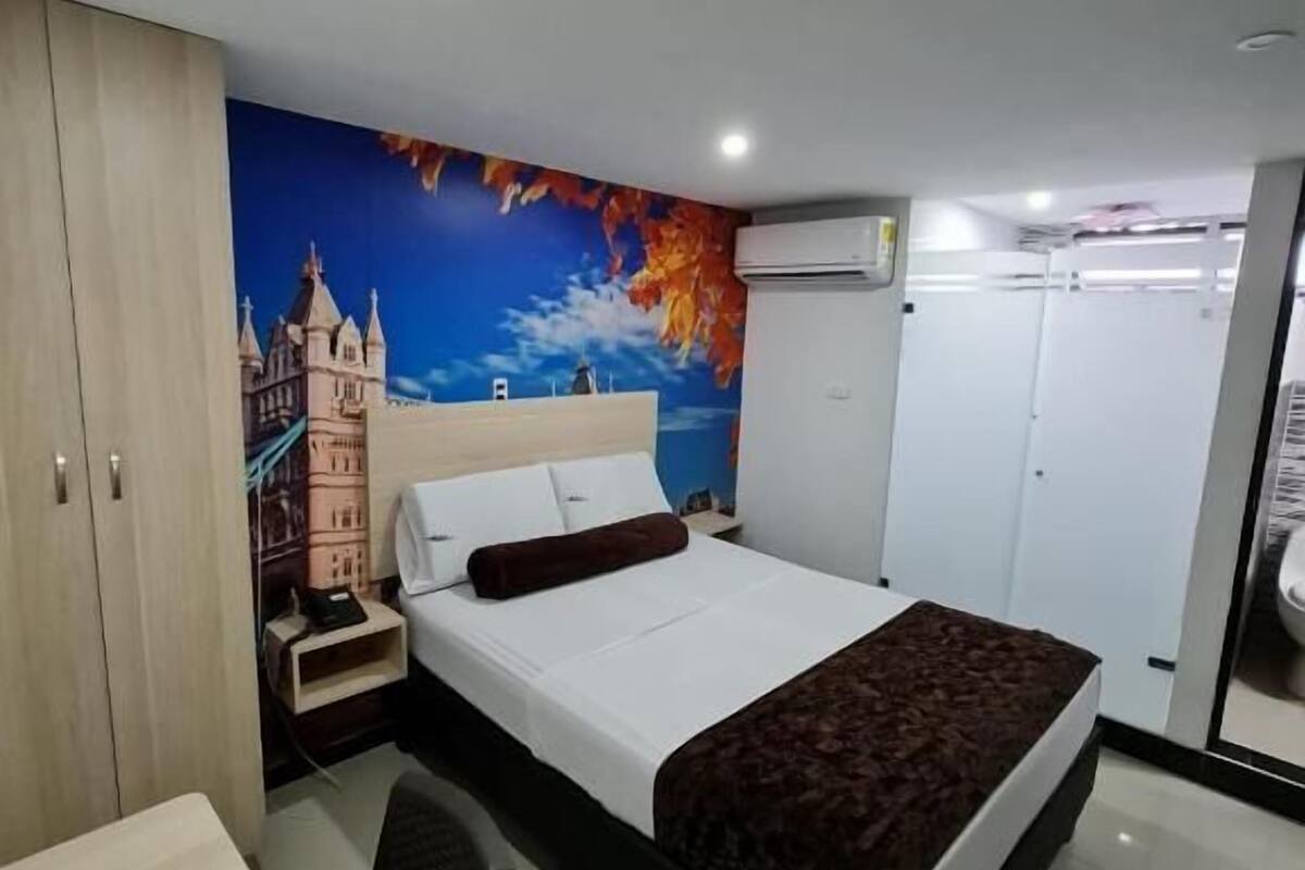 A hotel room with a bed, a desk, a wardrobe, and a bathroom.