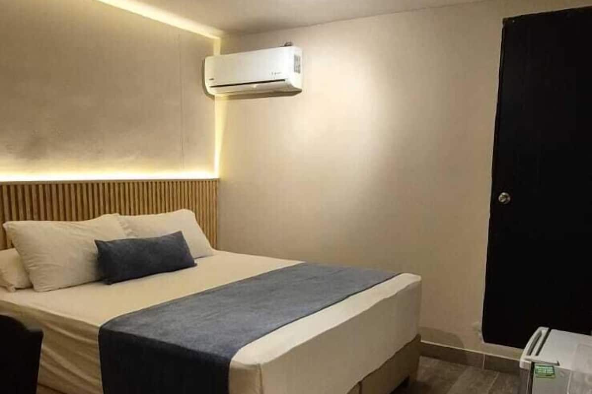 A bedroom with a bed, bedside table, and an air conditioning unit.