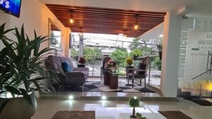 A modern living room with a white coffee table, a large potted plant, and a sofa. - HOTEL SURAMERICANA (Medellín)