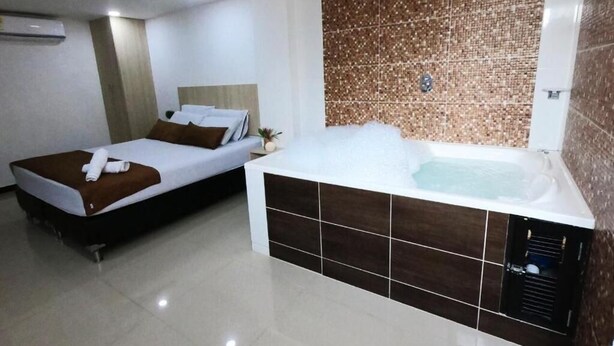 A hotel room with a bed, a separate sleeping area, and a large bathtub. - HOTEL SURAMERICANA (Medellín)