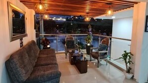 A modern living room with a sofa, two armchairs, a coffee table, and a balcony with a railing. - HOTEL SURAMERICANA (Medellín)
