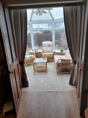 A sunroom with wicker furniture, a ceiling fan, and a view of a backyard.