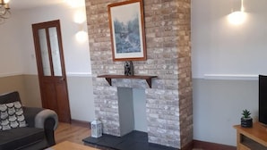 Un salon avec une cheminée en pierre, un canapé, une table basse et un meuble pour la télévision.