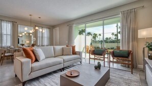 A modern living room with a sofa, coffee table, and chairs. There is a large window with a view of palm trees. - Dream home, prime location, themed bedrooms (Kissimmee)