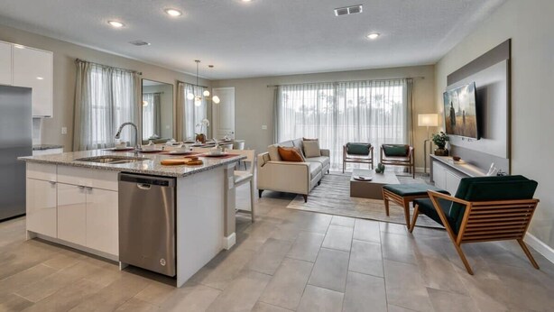 A modern kitchen with a central island, a dining area with a sofa and chairs, and a living room with a TV and seating. - Dream home, prime location, themed bedrooms (Kissimmee)