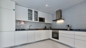 Una cocina moderna con armarios blancos, microondas integrado y una campana extractora de acero inoxidable.