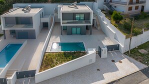Un edificio residencial moderno de varios pisos con piscina en la azotea y un jardín ajardinado.
