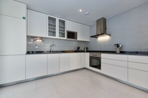 A modern kitchen with white cabinets, a built-in microwave, and a stainless steel range hood. - Villa Foz - Holiday Villa with Private Pool By SCH (Foz do Arelho)