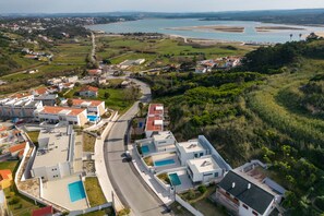 A residential area with modern houses, a road, and a large body of water in the background. - Villa Foz - Holiday Villa with Private Pool By SCH (Foz do Arelho)