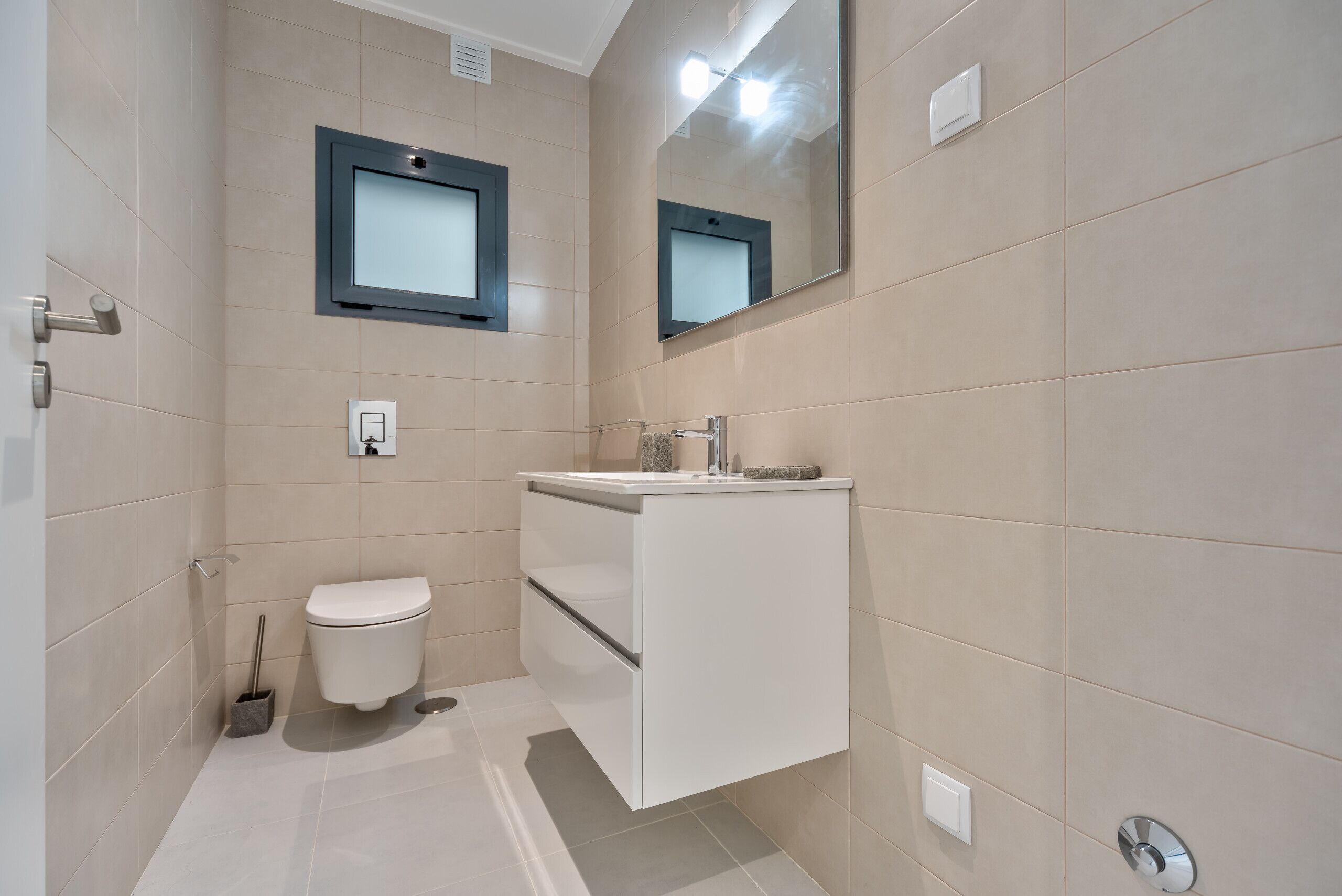 A modern bathroom with a toilet, sink, and mirror.