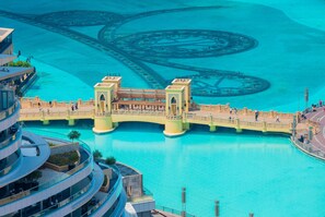 A bridge over a turquoise body of water with a modern building on the left and a landscaped area on the right.