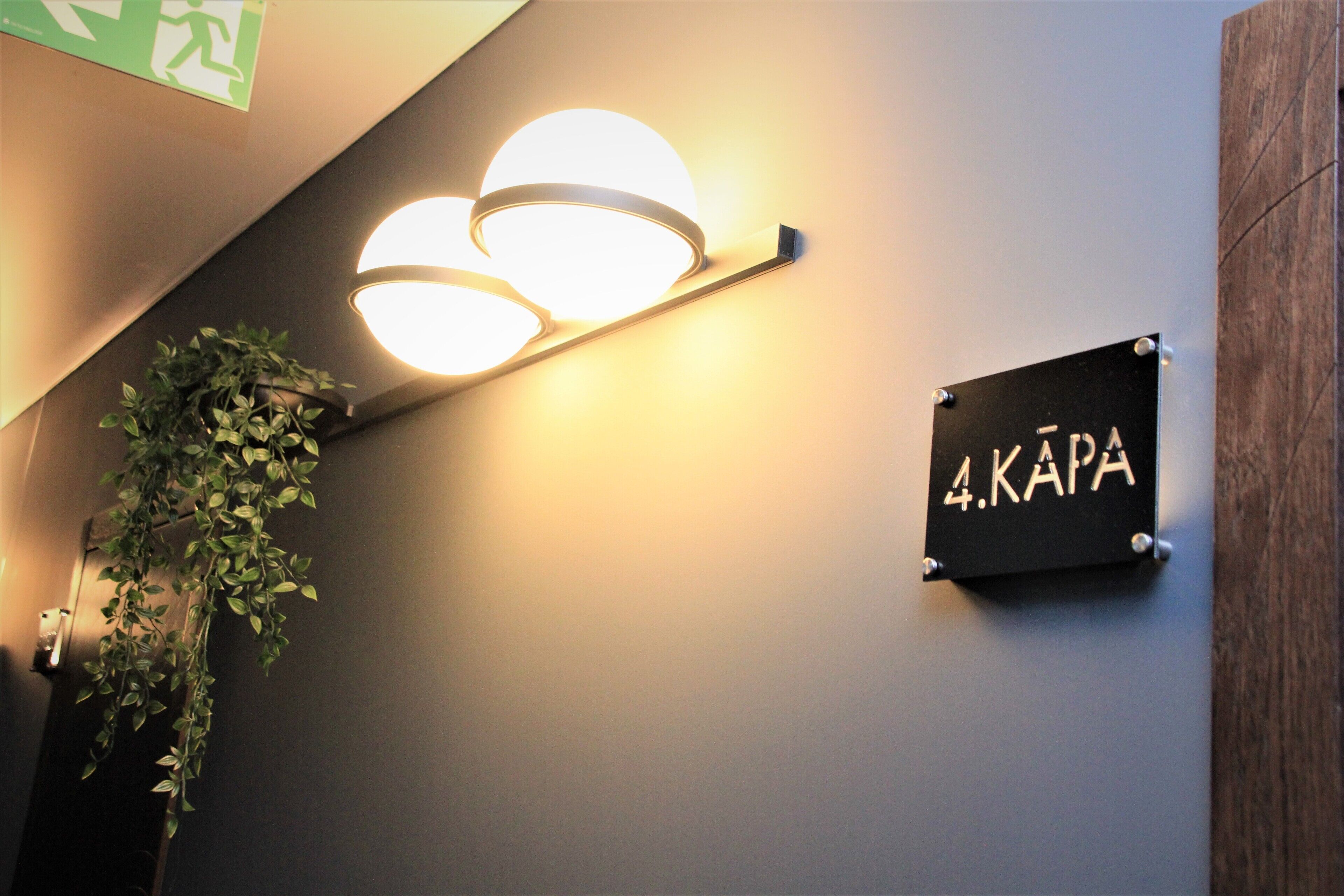 A wall-mounted sign with the number 4 and the word "KAPA" indicating room number.