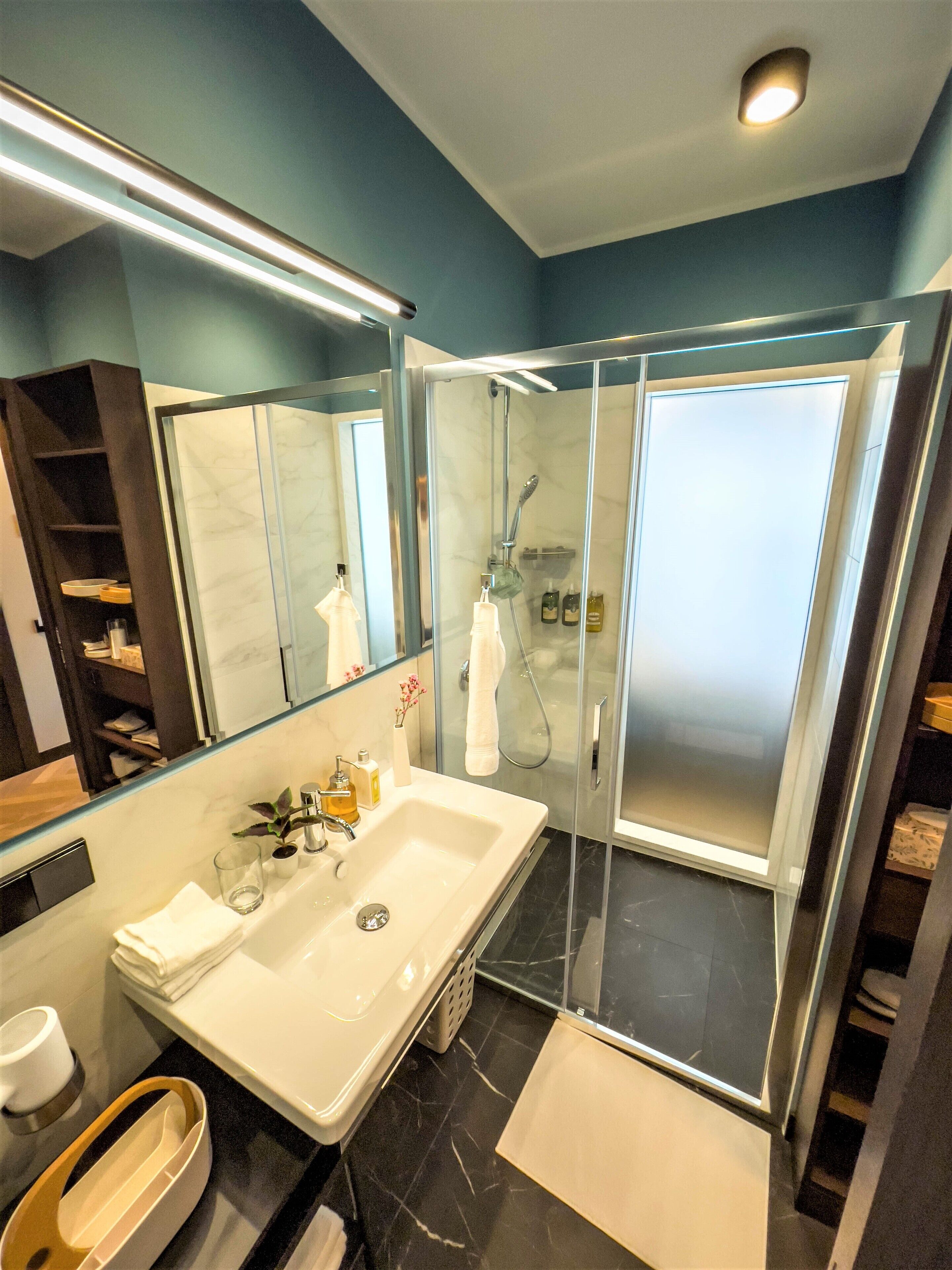 A modern bathroom with a glass-enclosed shower, a large sink, and a mirror above it.