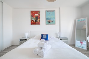 Ein Hotelzimmer mit einem großen Bett, zwei Nachttischen, einem Spiegel und zwei Bildern an der Wand.