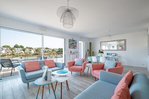 Una sala de estar moderna con balcón, ventanas amplias y mobiliario contemporáneo.