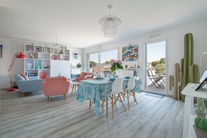 A modern living room with a dining area, white walls, and a large window.