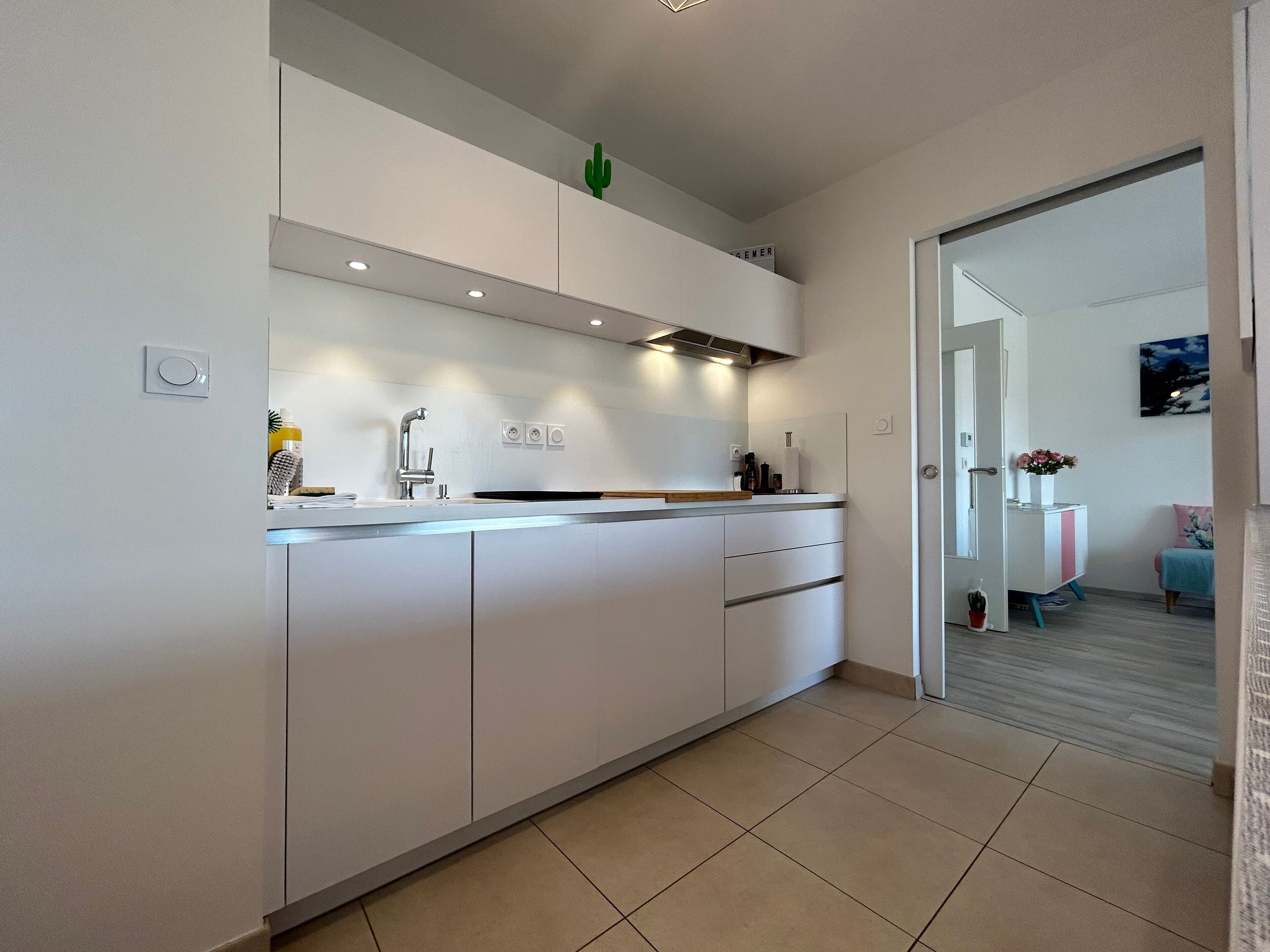 A modern kitchen with white cabinetry, a built-in oven, and a small island with a sink.
