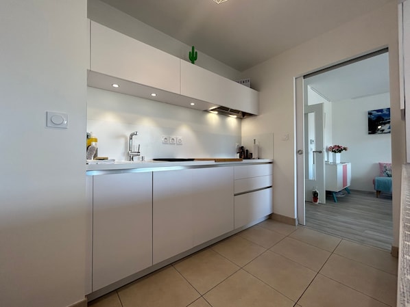 A modern kitchen with white cabinetry, a built-in oven, and a small island with a sink.