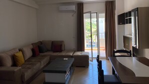A living room with a sofa, a coffee table, a TV, and a sliding glass door to the outside. - Jey Vlora Apartaments (Vlorë)