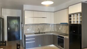 A modern kitchen with grey cabinets, a black refrigerator, and a built-in oven. - Jey Vlora Apartaments (Vlorë)
