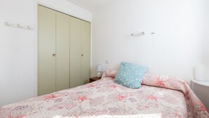 Un dormitorio con cama, armario, mesita de noche y lámpara.