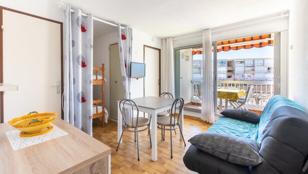 Una habitación con una mesa de comedor, sillas, un sofá y un balcón que ofrece vistas a edificios.