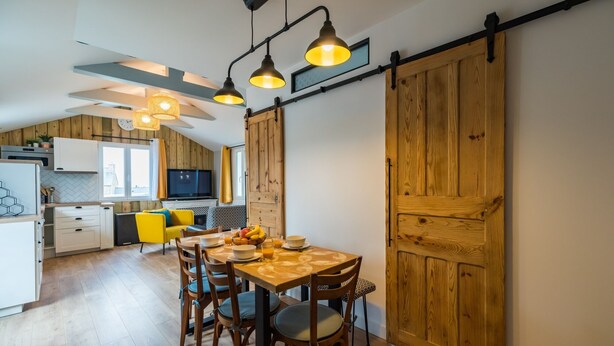 Una cucina moderna con mobili in legno, un tavolo da pranzo per quattro persone e un'ampia porta scorrevole in stile rustico.