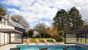 Une piscine avec des chaises longues et un espace salon abrité.