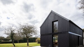 Un bâtiment moderne à deux étages, doté d’une façade sombre et d’une grande fenêtre à l’étage supérieur.