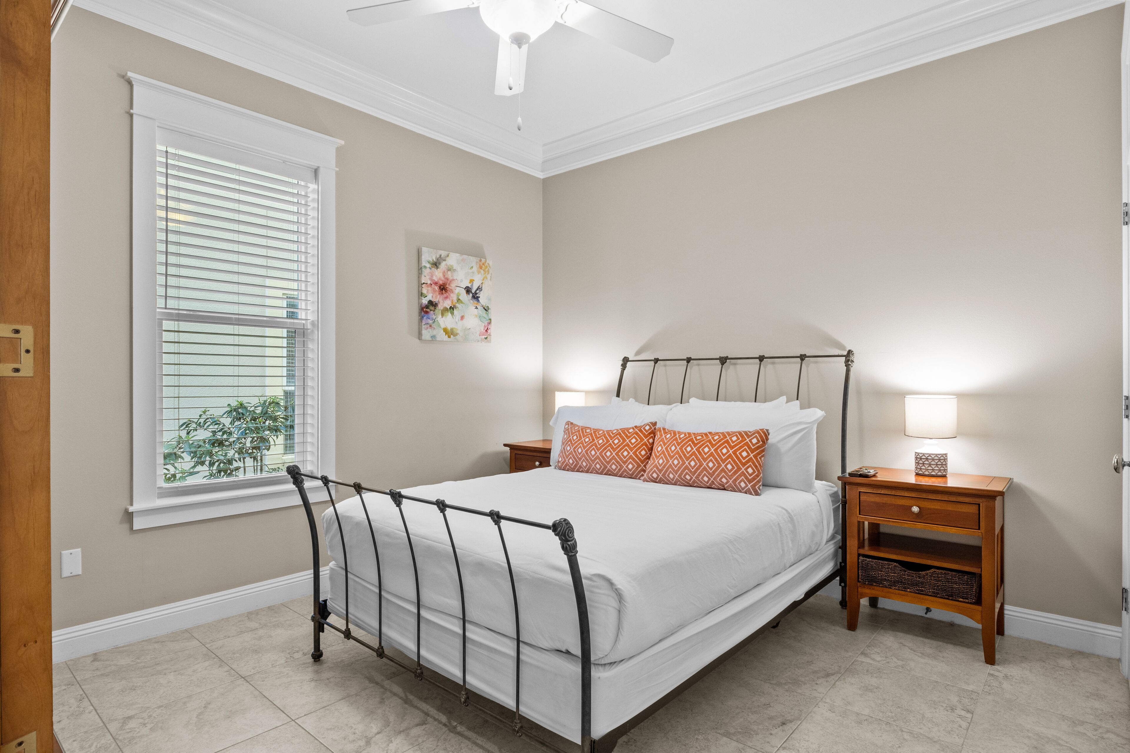 A bedroom with a bed, nightstands, a window with blinds, and a ceiling fan.