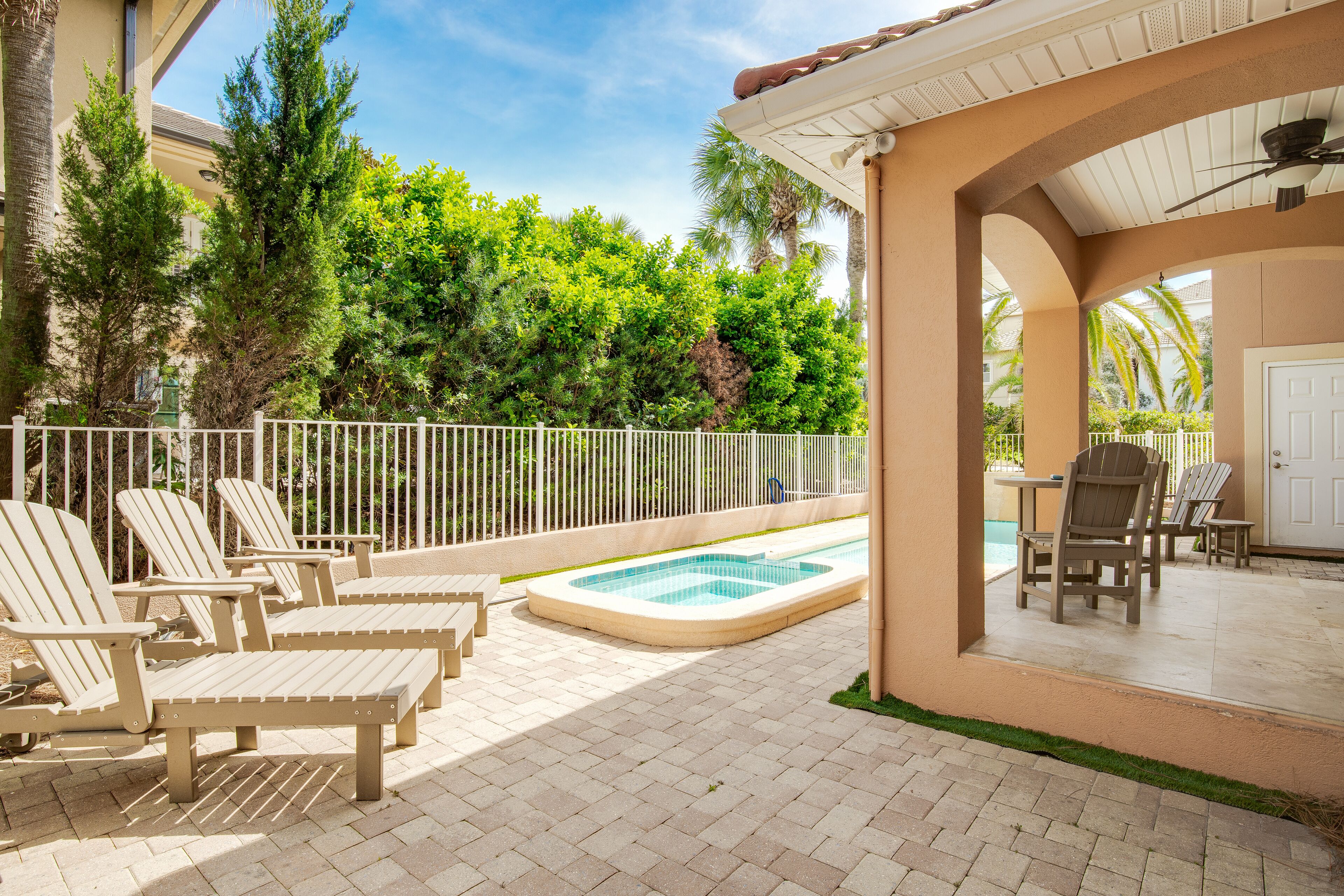 Un espace aménagé au bord de la piscine, avec des chaises longues, une petite piscine et un patio couvert avec une porte.