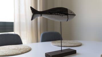 A table with a fish-shaped decoration on a stand, two woven placemats, and a chair in the background.