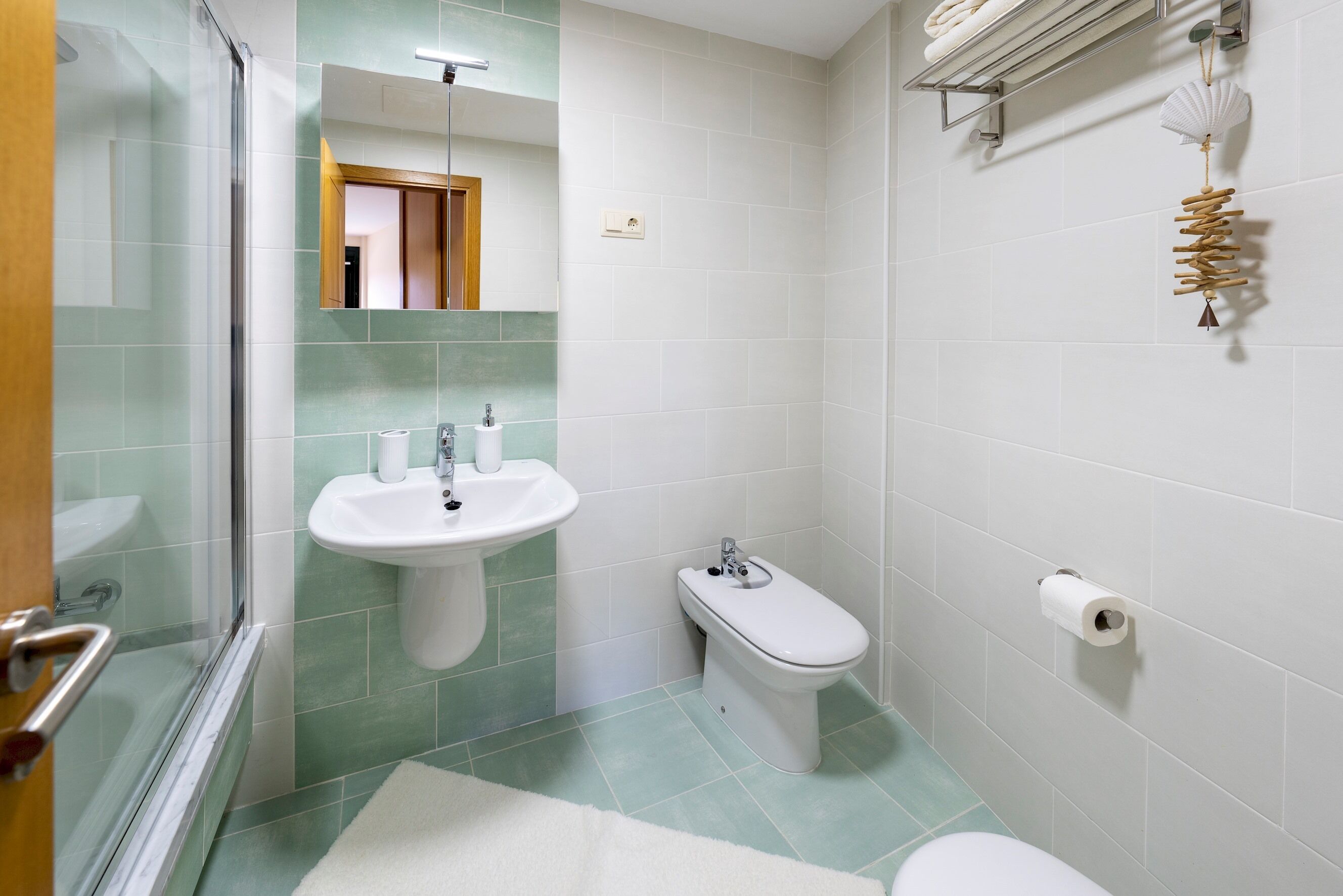 Une salle de bain avec une douche à parois de verre, un lavabo, un bidet et des toilettes.